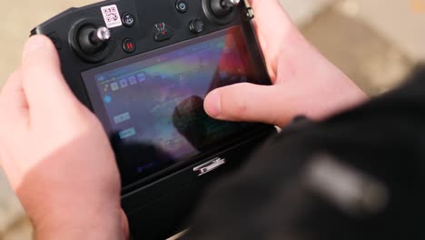 man controlling a drone controller touch screen - steady over the shoulder