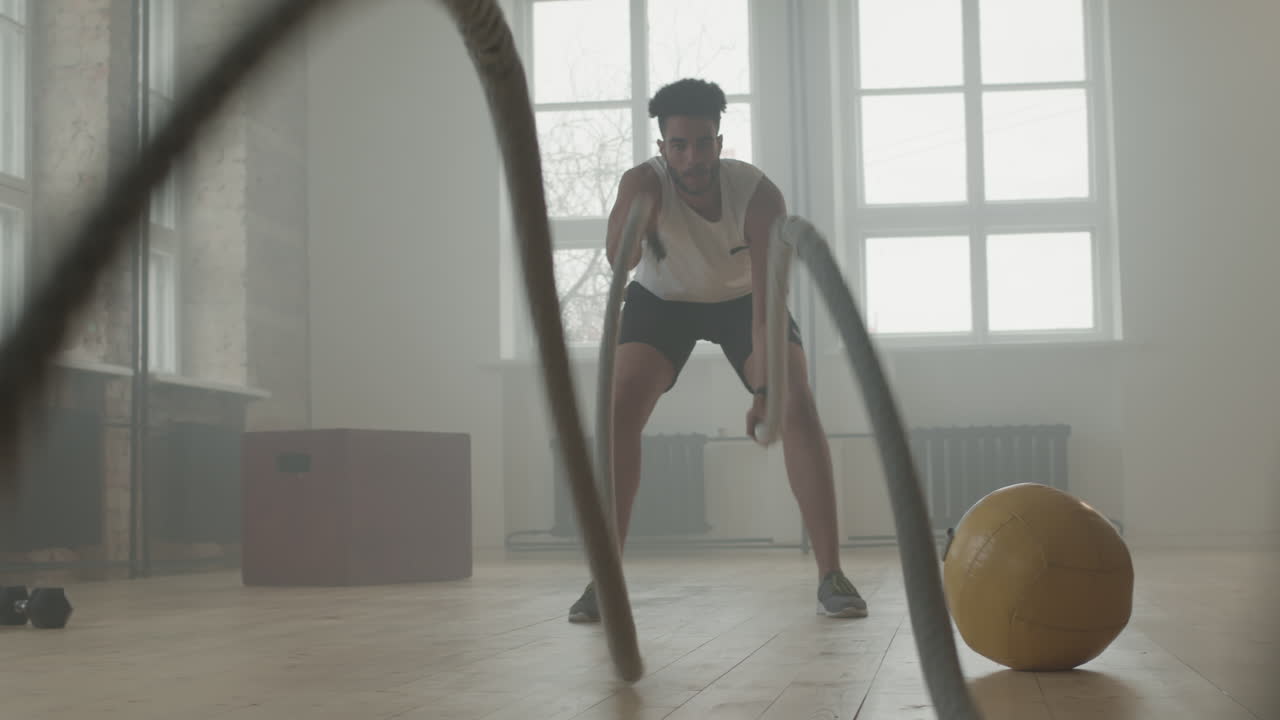 Strong Man With Battle Rope In Gym