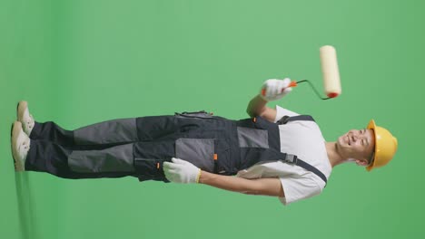 full body of side view asian man painter wearing safety helmet painting and smiling in the green screen background studio