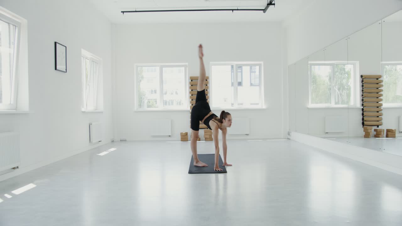 mujer haciendo una postura de yoga en un estudio