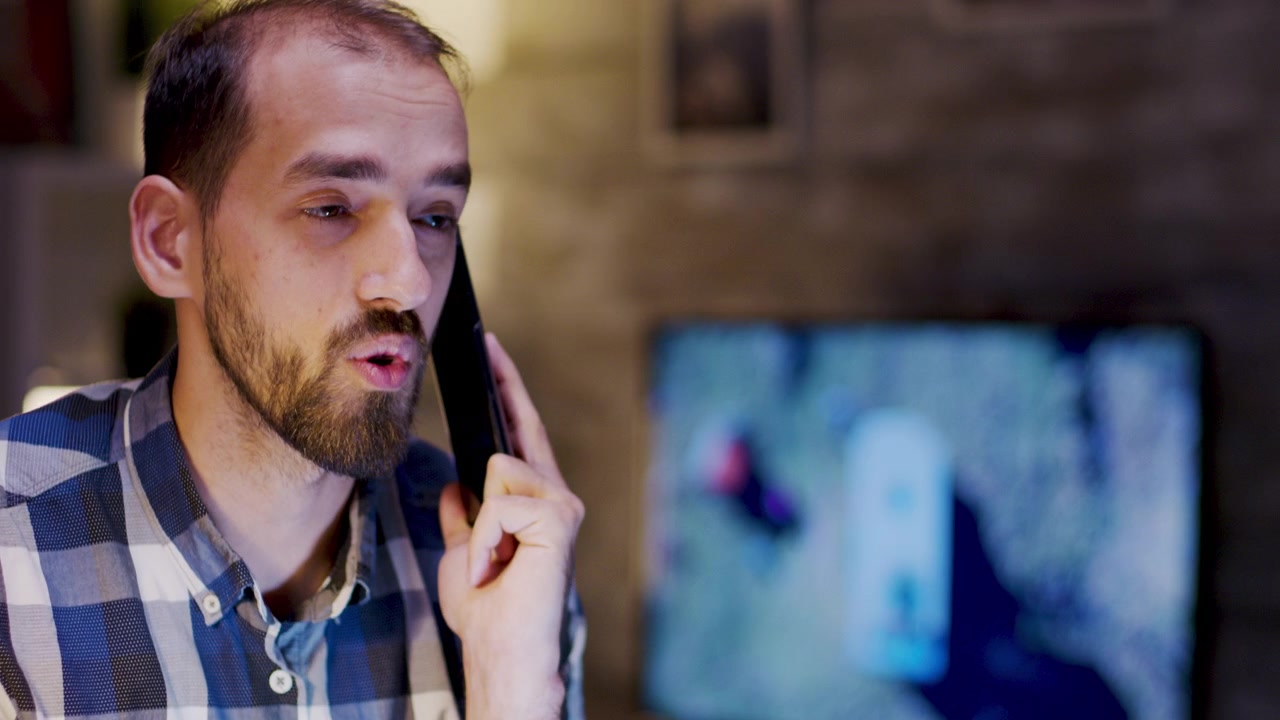 Young Man Talking on Smartphone While Working at Home
