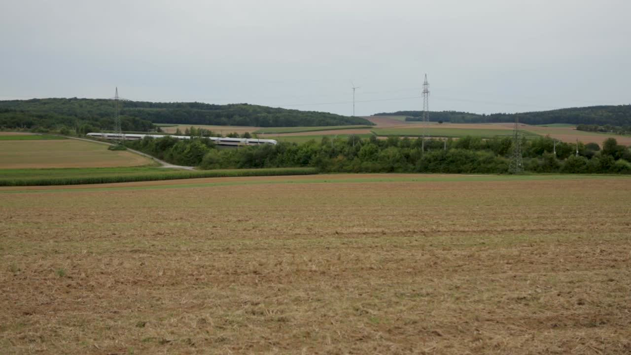 высокоскоростные поезда движутся по сельской местности с полями и ветряными турбинами