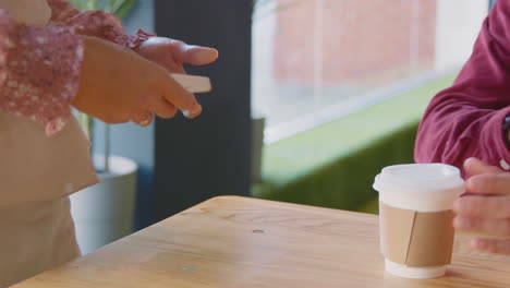 Close-Up-Of-Man-Making-Purchase-In-Coffee-Shop-Using-Debit-Or-Credit-Card