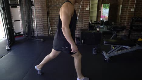 tattoo man muscles in home gym doing static lunge side shot