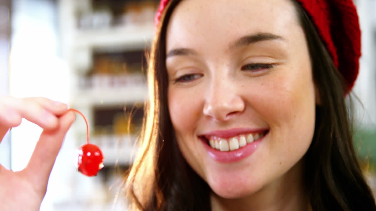 체리를 들고 있는 미소 짓는 여자