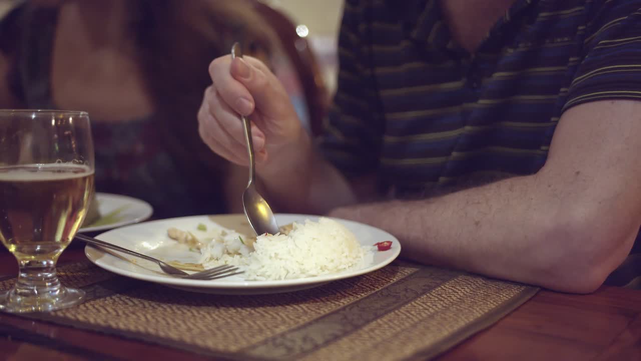 primer plano interior de un hombre separando el arroz que quiere comer del montón de arroz en su plato con una cuchara en un restaurante