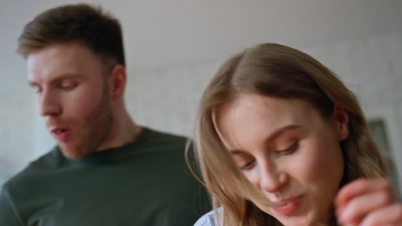 Closeup woman eating fruit home kitchen. Wife biting veggie giving to boyfriend