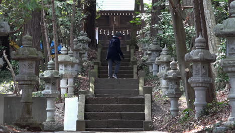 a adult man calls with his arm to climb up the old stairs at of a japaneses shrine