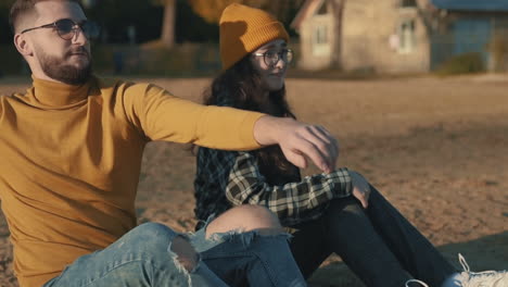 young female and male friends sharing moments sitting on the beach.