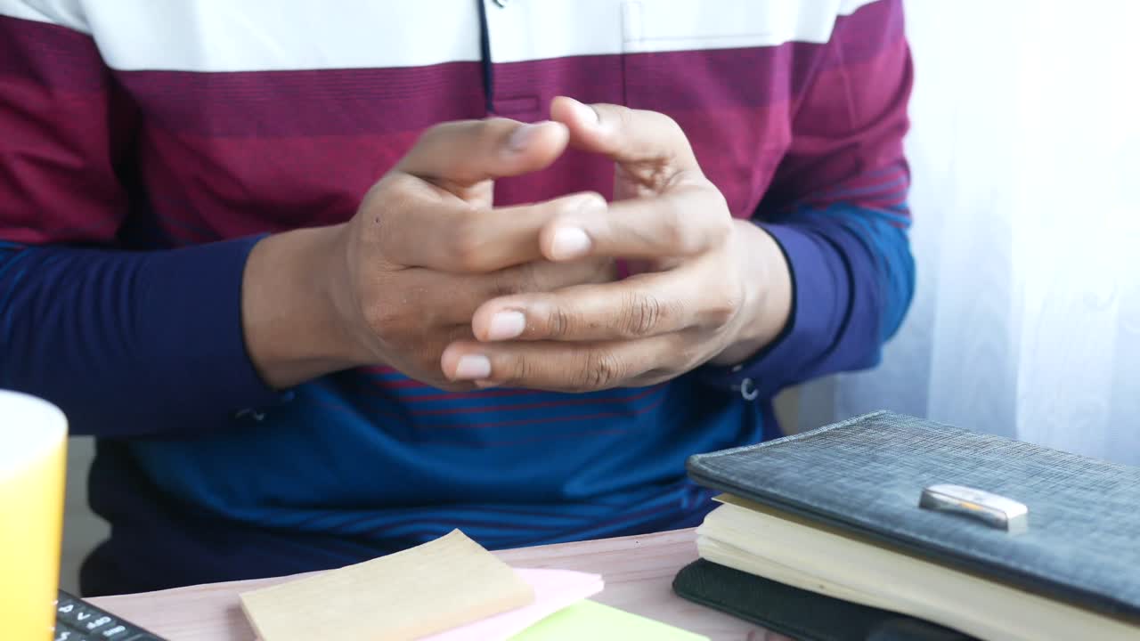 persona sentada en un escritorio con las manos juntas