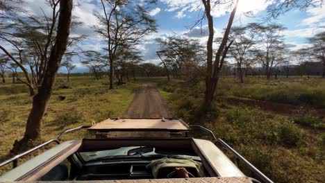 safari vehicle with top open driving on savannah of lake nakuru national parks in kenya