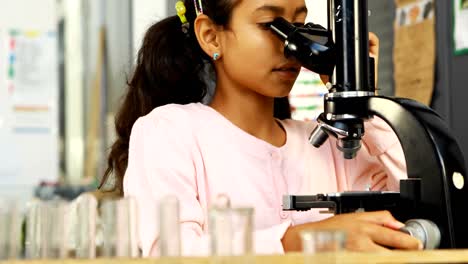 un escolar haciendo un experimento con un microscopio 4k.