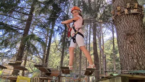 little child girl with harness having fun at adventure park