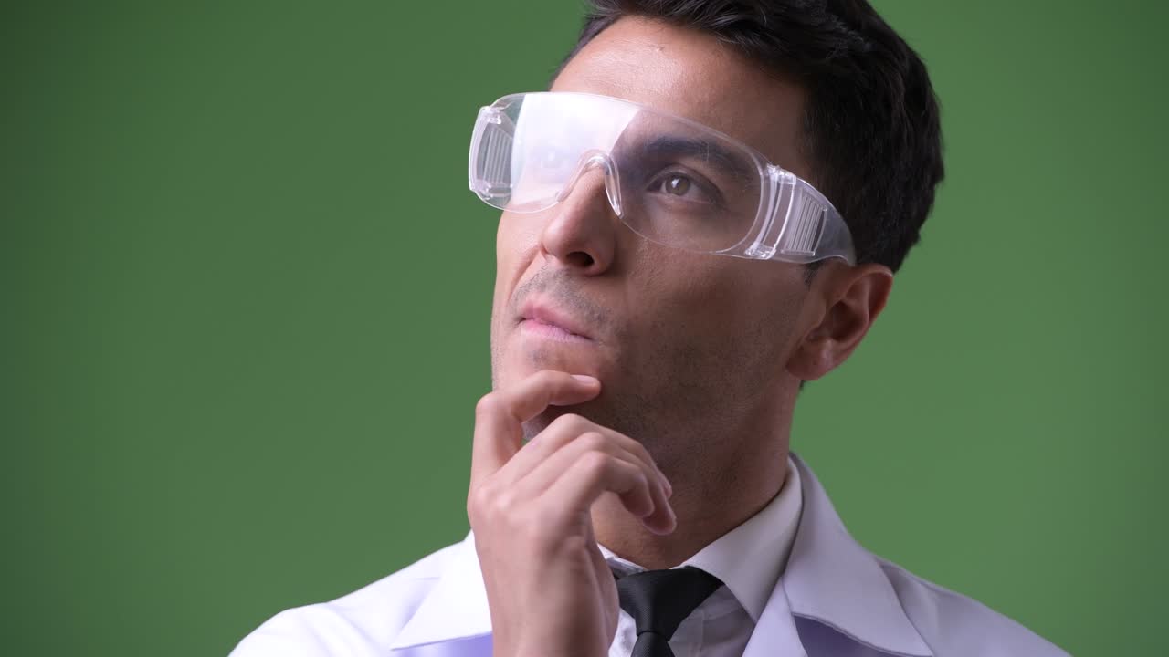 joven hombre hispano guapo médico contra fondo verde