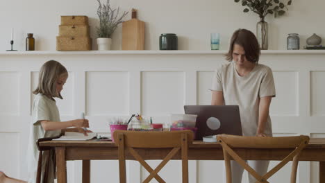 a mother makes a work video call at home with her pretty blonde daughter while she does her homework