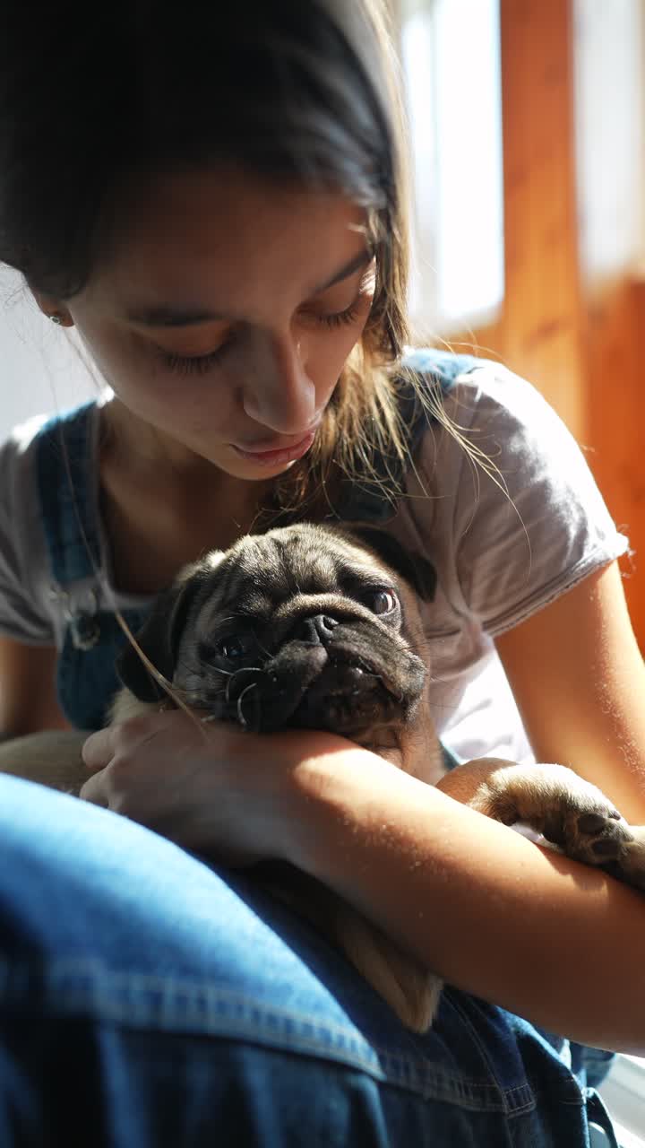 Niña acurrucando a un cachorro pug