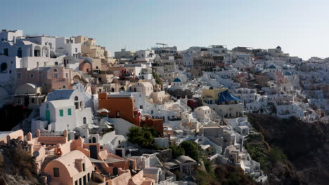 Casas-Y-Edificios-Blancos-En-La-Ciudad-De-Oia-En-La-Isla-De-Santorini,-Grecia---Retroceso-Aéreo