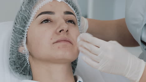cosmetologist prepares woman's face for a beauty treatment