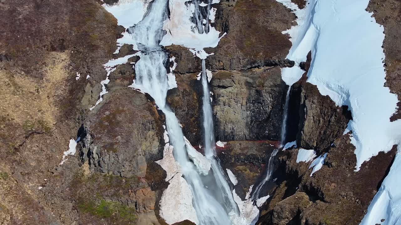 la magnífica cascada de rjúkandi en islandia captura la belleza de una montaña cubierta de nieve en una fotografía impresionante.