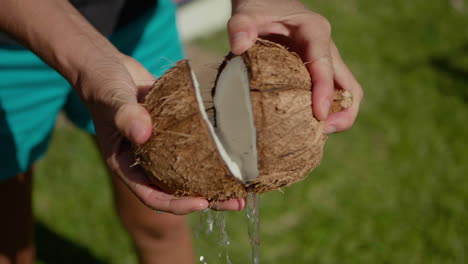 Woman-opens-freshly-cut-coconut,-water-spills-out