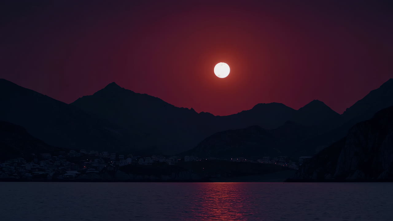 Dramatic Red Moon Over Mountain Village and Water at Night