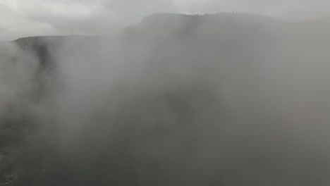 volando a través de una espesa niebla que revela un hermoso paisaje montañoso verde y un lago, pueblo chic-chocs, gaspesiano