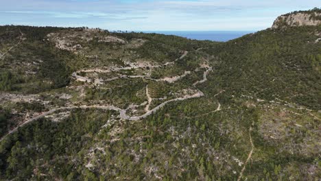 Winding-road-through-Serra-de-Tramuntana,-Mallorca,-sunny-day,-aerial-view