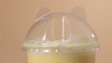 close up on the top of fancy mango milkshake plastic cup, put in black straw