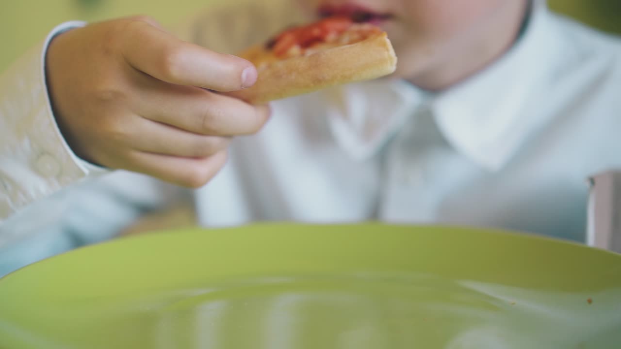 chico en camisa tiene almuerzo con pizza fresca en la mesa de cerca