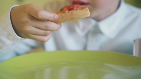 chico en camisa tiene almuerzo con pizza fresca en la mesa de cerca