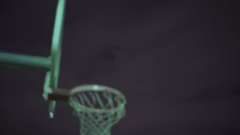 girl shoots basketball in net at night