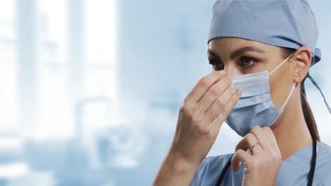 Caucasian-female-surgeon-wearing-face-mask-against-blurred-background