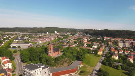 Vista-Escénica-Lejana-De-La-Famosa-Iglesia-Fassberg-Rodeada-De-árboles-Frondosos-En-La-Ciudad-De-Molndal,-Suecia---Disparo-Ascendente-De-Drones