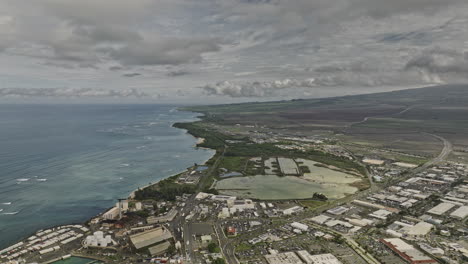 Kahului-Maui-Hawaii-Aerial-v8-drone-flyover-town-center-capturing-landscape-of-coastal-island,-main-airport-and-residential-areas-with-storm-clouds-in-the-sky---Shot-with-Mavic-3-Cine---December-2022