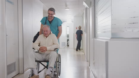 Männlicher-Pfleger-Schiebt-älteren-Männlichen-Patienten,-Der-Im-Rollstuhl-Aus-Dem-Krankenhaus-Entlassen-Wird