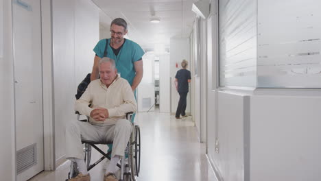 hombre que empuja a un paciente de edad avanzada que es dado de alta del hospital en silla de ruedas