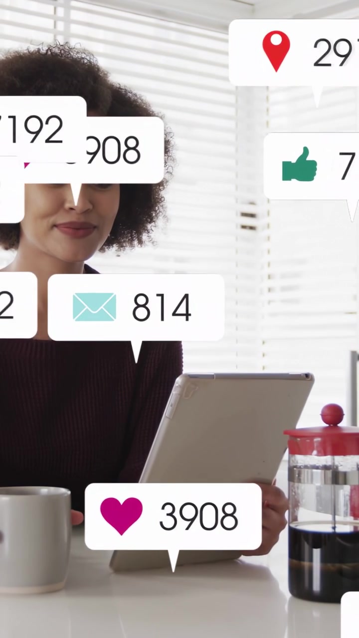 Vertical video: Woman checking tablet at counter, social alerts piling up, sipping mug, settling