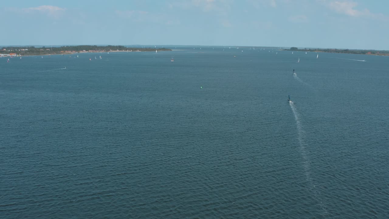 drone - toma aérea de un surfista en un mar azul, ondulado y ventoso en un día soleado con nubes blancas en una isla, 30p