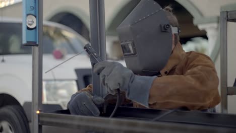 welder fabricating steel framework using stick welder slow motion shot