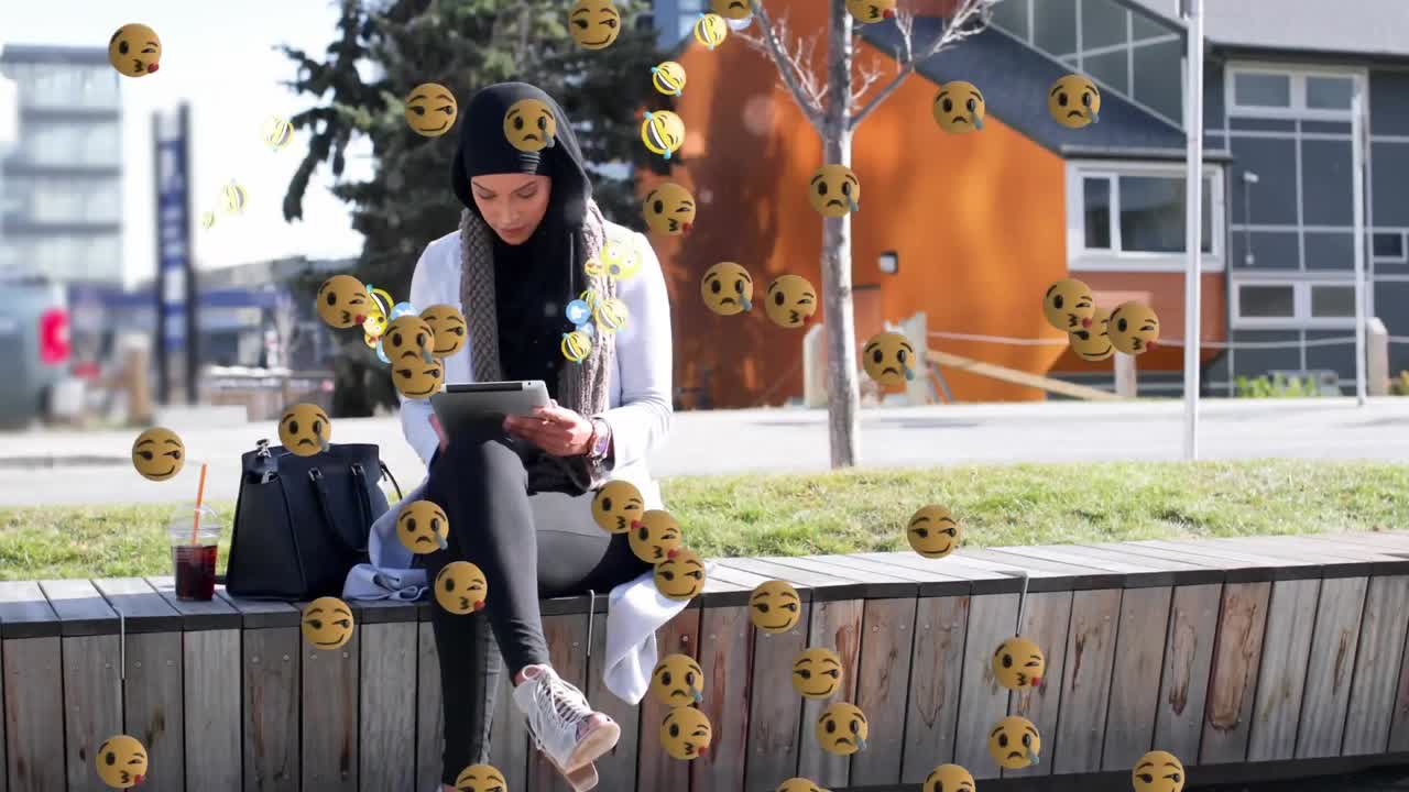 emojis que se mueven contra la mujer en hijab usando una tableta digital
