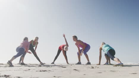 mujeres mayores estirándose en la playa