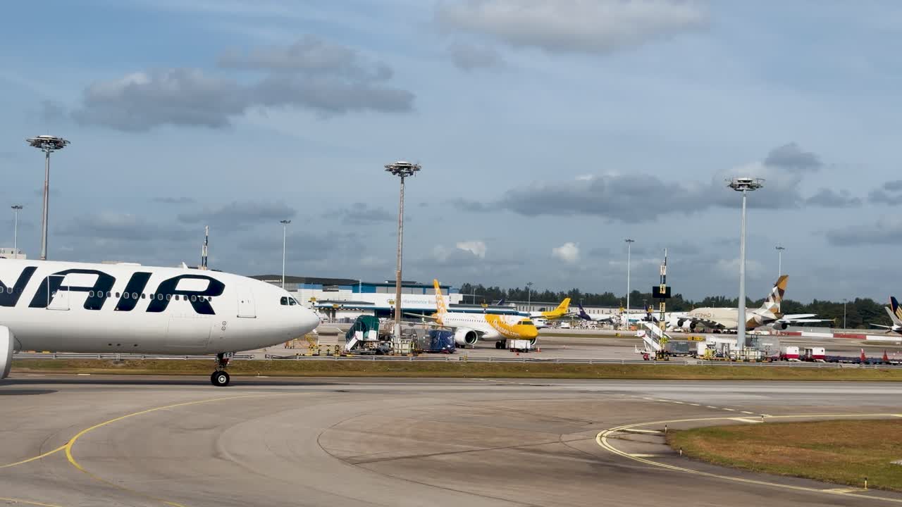 Un grande aereo di linea commerciale bianco rulla lentamente sulla pista in un trafficato aeroporto internazionale