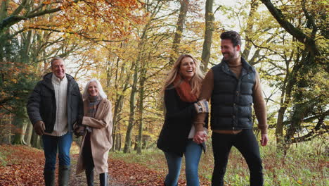 multi-generation family walks along path through autumn countryside with children running ahead