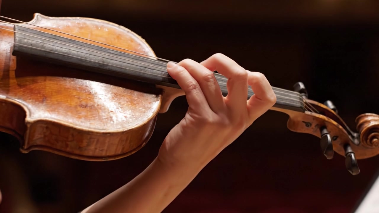 Uno Sguardo Ravvicinato a un'Artistica Esibizione di Violino: Le Mani Graziose di un Musicista Che Danno Vita a Melodie Attraverso un'Abile Tecnica dell'Archetto e il Posizionamento delle Dita
