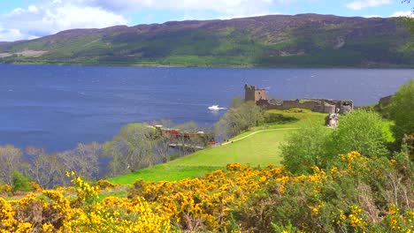 an establishing shot of loch ness castle scotland with speedboat passing