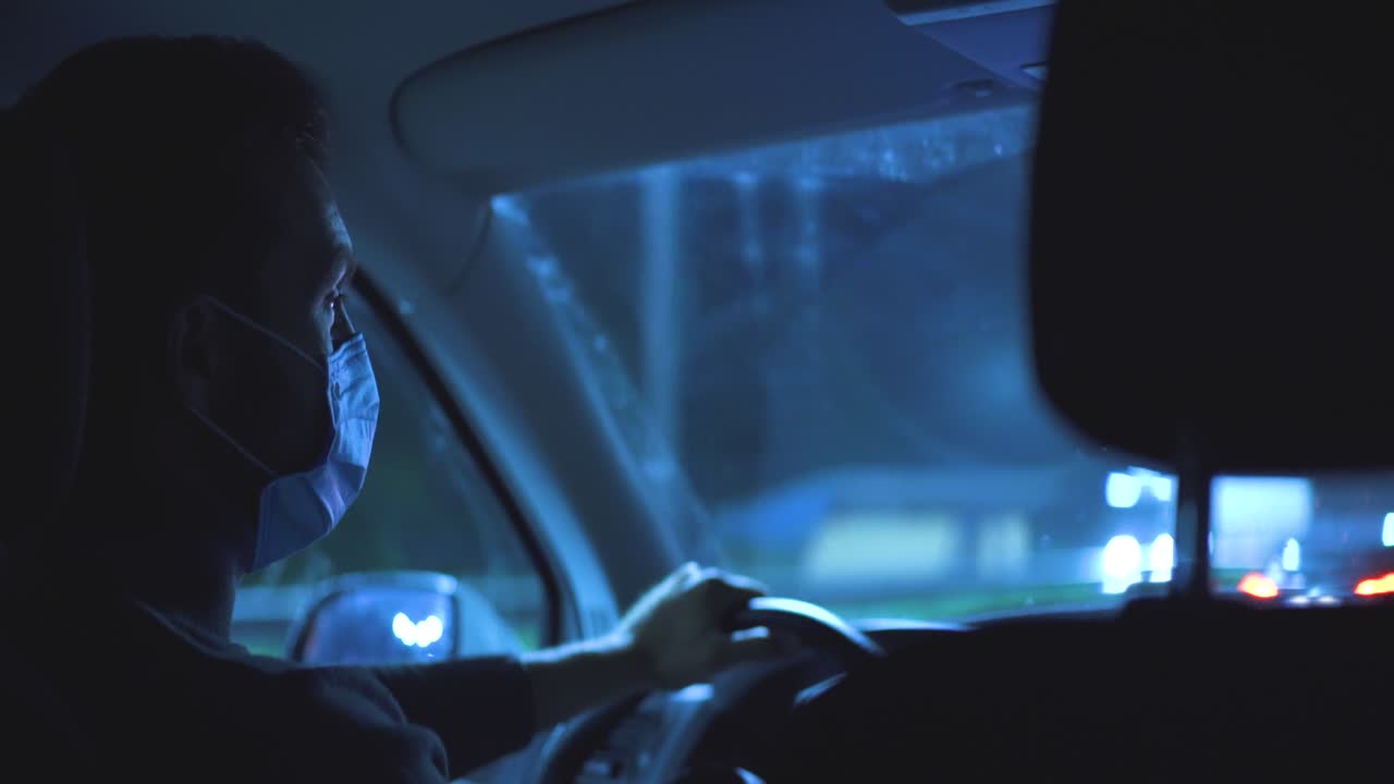 야간 고속도로에서 운전하는 의료 마스크를 입은 남자