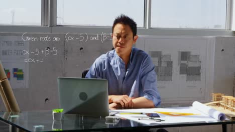 animation of mathematical equation and diagrams, asian architect designing blueprint on laptop