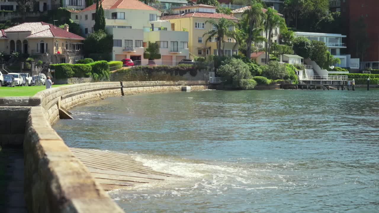 Wide shot of a curved sandstone seawall and concrete boat ramp along ...
