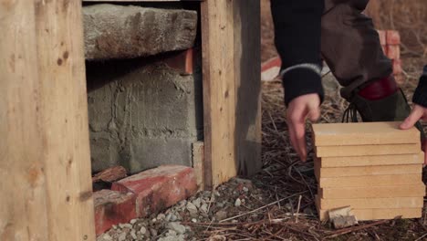 the man places a pile of wooden planks near the diy hot tub - close up