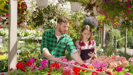 Two-Gardeners-doing-paperwork-between-plants